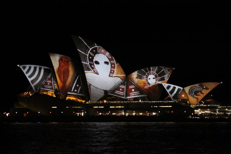 The Sydney Opera House at night with bright projections on its surfaces during the Vivid Festival. In 2016 the inspiration was Aboriginal art.