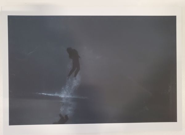 black and white photo of person diving under still water in the ocean