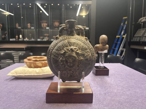 Bronze decorative vessel featuring a medusa head motif on display. Ornate metal artifact	Ornamental bronze vessel with classical sculptural detailing. Museum display piece	Ancient bronze vessel exhibited in professional museum setting.