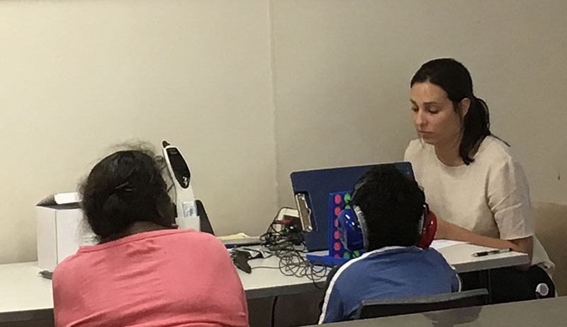 An audiology student assessing a child’s hearing