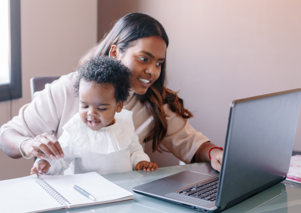Mother with baby on lap while working on a computer