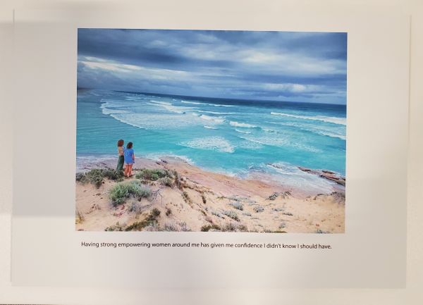 two women stand on beach looking out at blue ocean