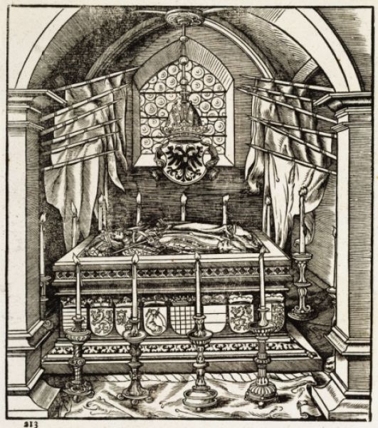 A coffin surrounded by flags and candlestick