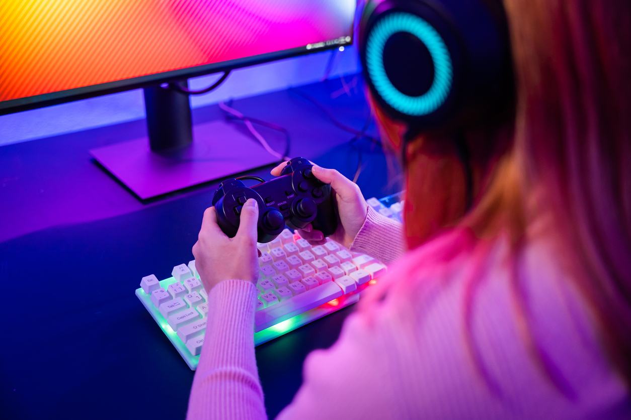 A woman gaming with a playstation controller and monitor