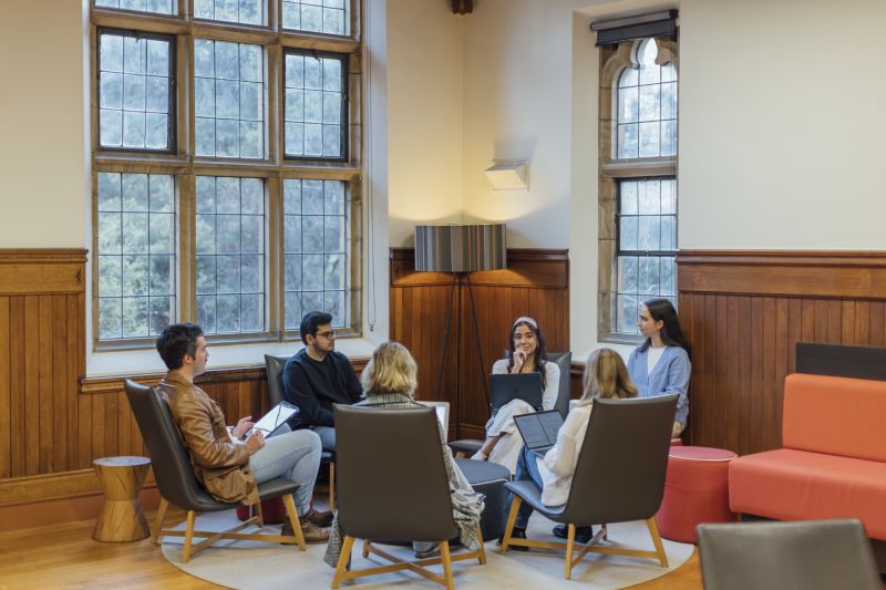 Postgraduate students sitting in a circle talking in Arts Hall