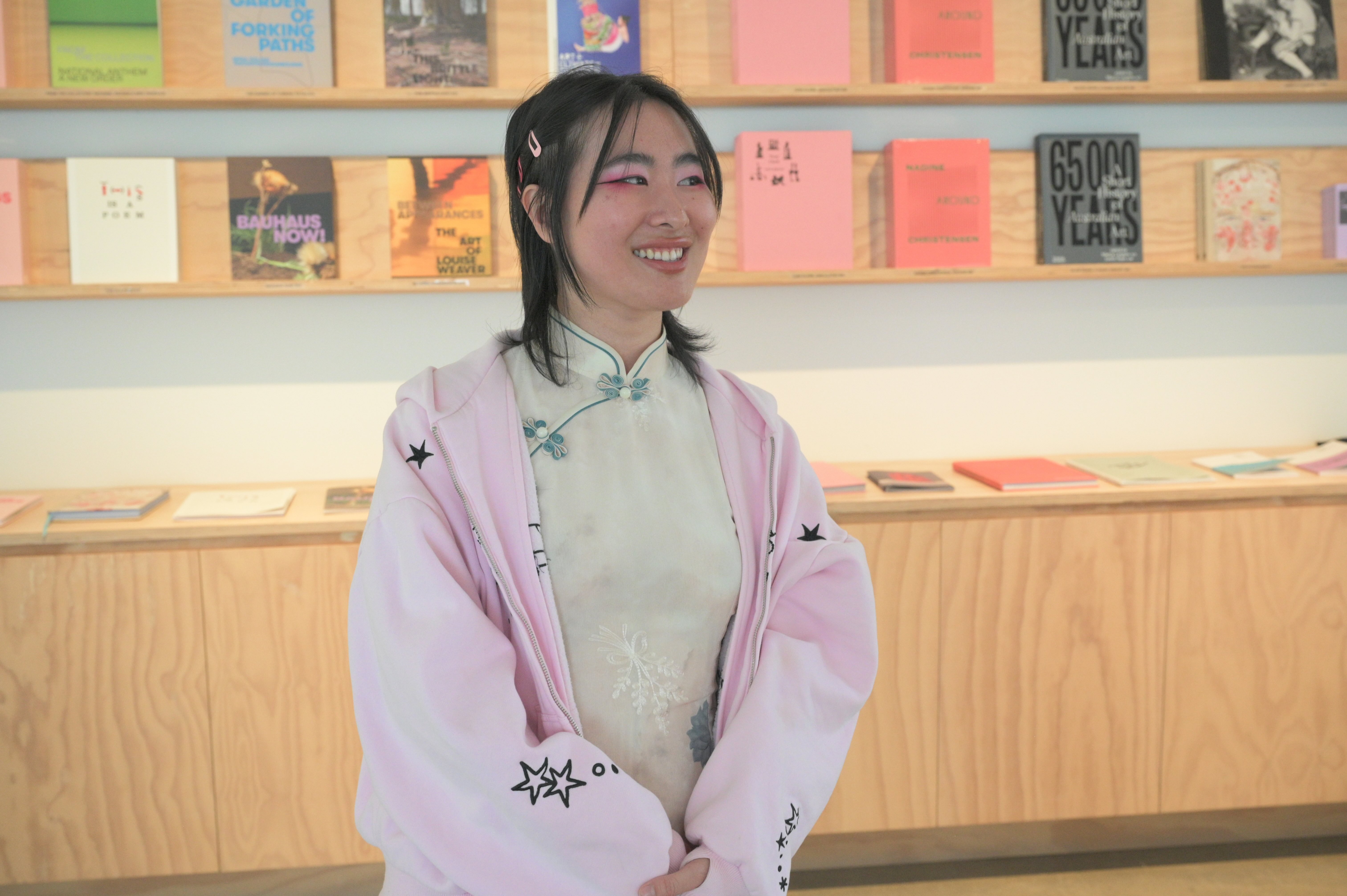 A woman stands in a light-filled gallery smiling