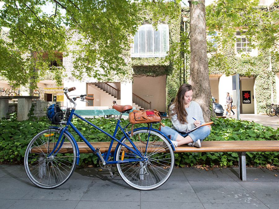 A girl sitting on a bench, reading a book