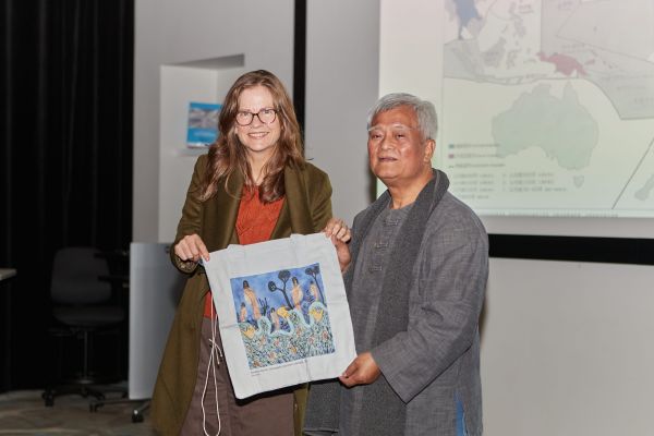 Two people holding a printed tote bag