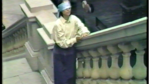 A person holds the railing of and outdoor marble staircase while blindfolded