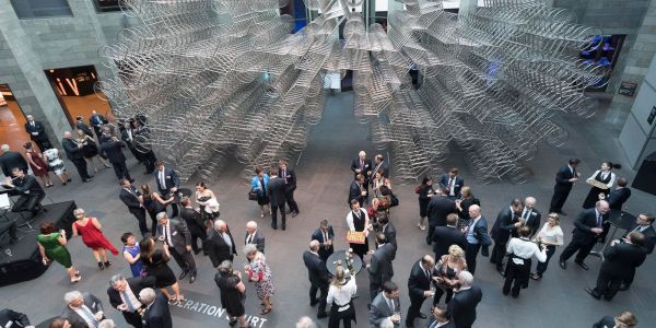 Overhead shot of an event with dozens of people socialising at the National Gallery of Victoria