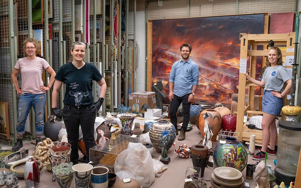Four students standing amongst art works and sculptures