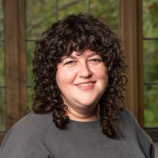 women with brown curly hair infront of big window back drop