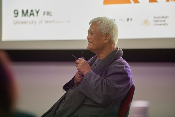 A person sitting in a chair speaking into a microphone