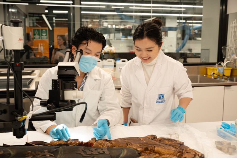 Students of the Grimwade Centre, Zeejay Tan and Chuqing Huang, engaged in restoration of an object of cultural and historical significance