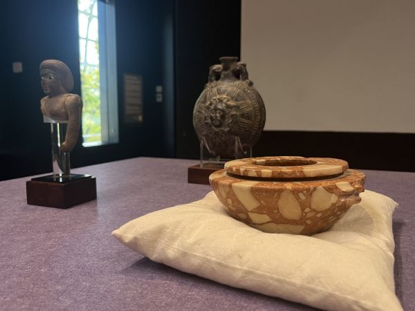 Ancient marble bowls and bronze vessel displayed together in museum setting.
