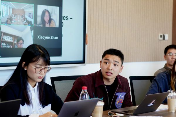 A person engaging in group discussion and person looking at laptops
