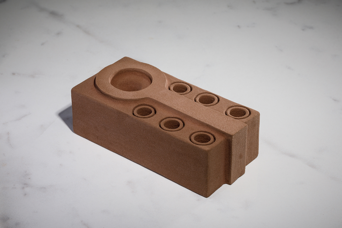 Brown hand-carved, biodegradable florist oasis foam in the shape of a sculptural brick.