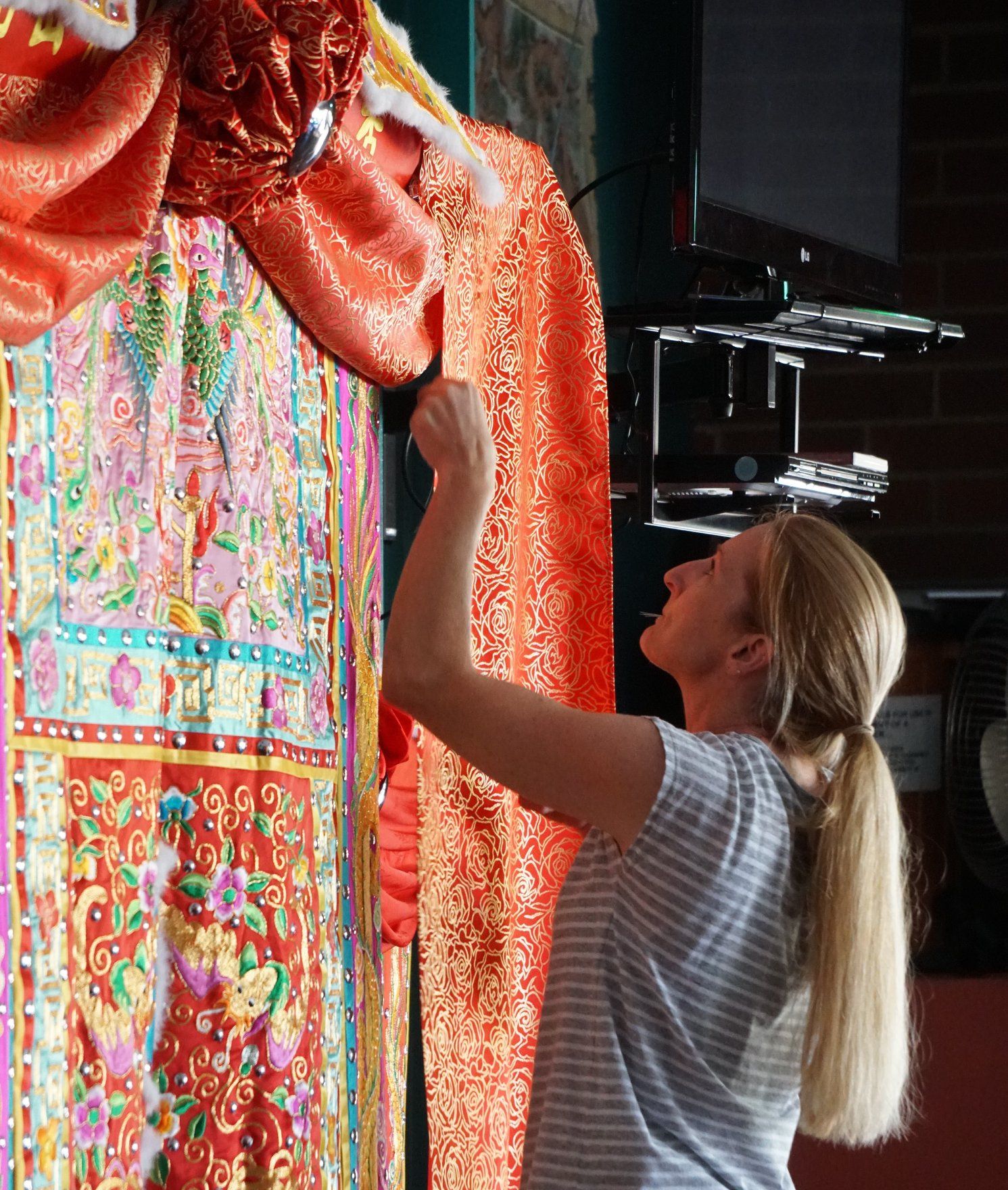 A volunteer adjusts a display of fabric at the Golden Dragon Museum, Bendigo. 